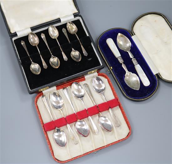 Two cased sets of silver coffee spoons and a cased pair of silver and mother of pearl butter? servers.